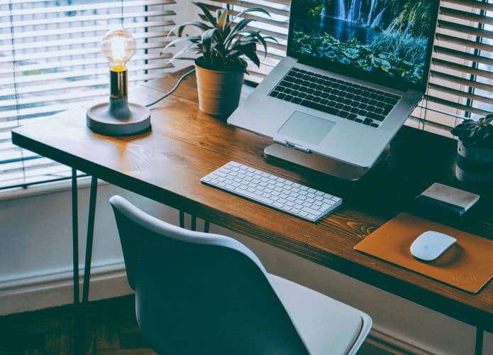 imagem mostra um home office com notebook, mouse e teclado
