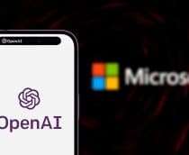 iPhone exibindo logomarca da OpenAI na tela colocado na frente de imagem da logomarca da Microsoft