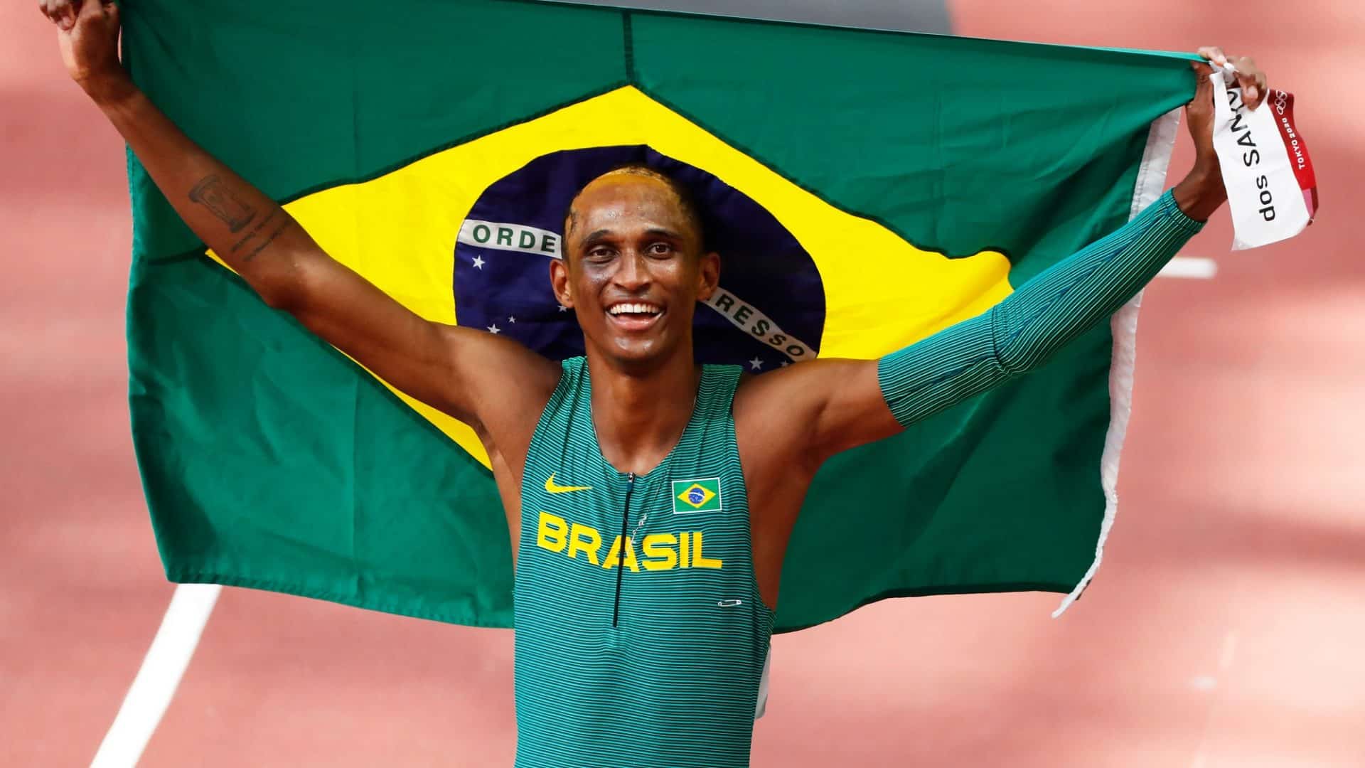 alison dos santos com a bandeira do brasil