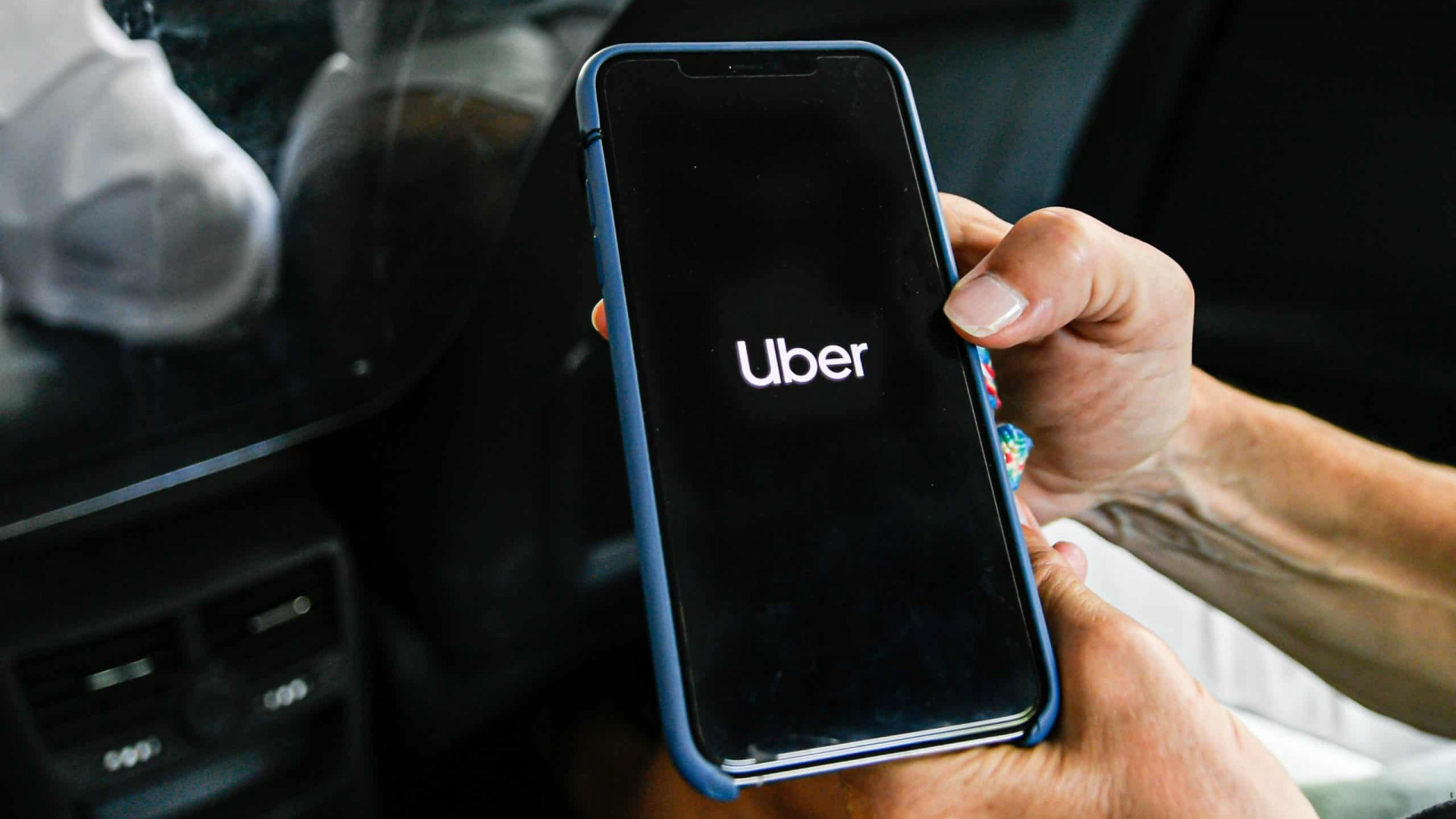 Pessoa segurando iPhone enquanto abre aplicativo do Uber