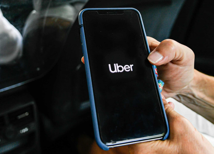 Pessoa segurando iPhone enquanto abre aplicativo do Uber
