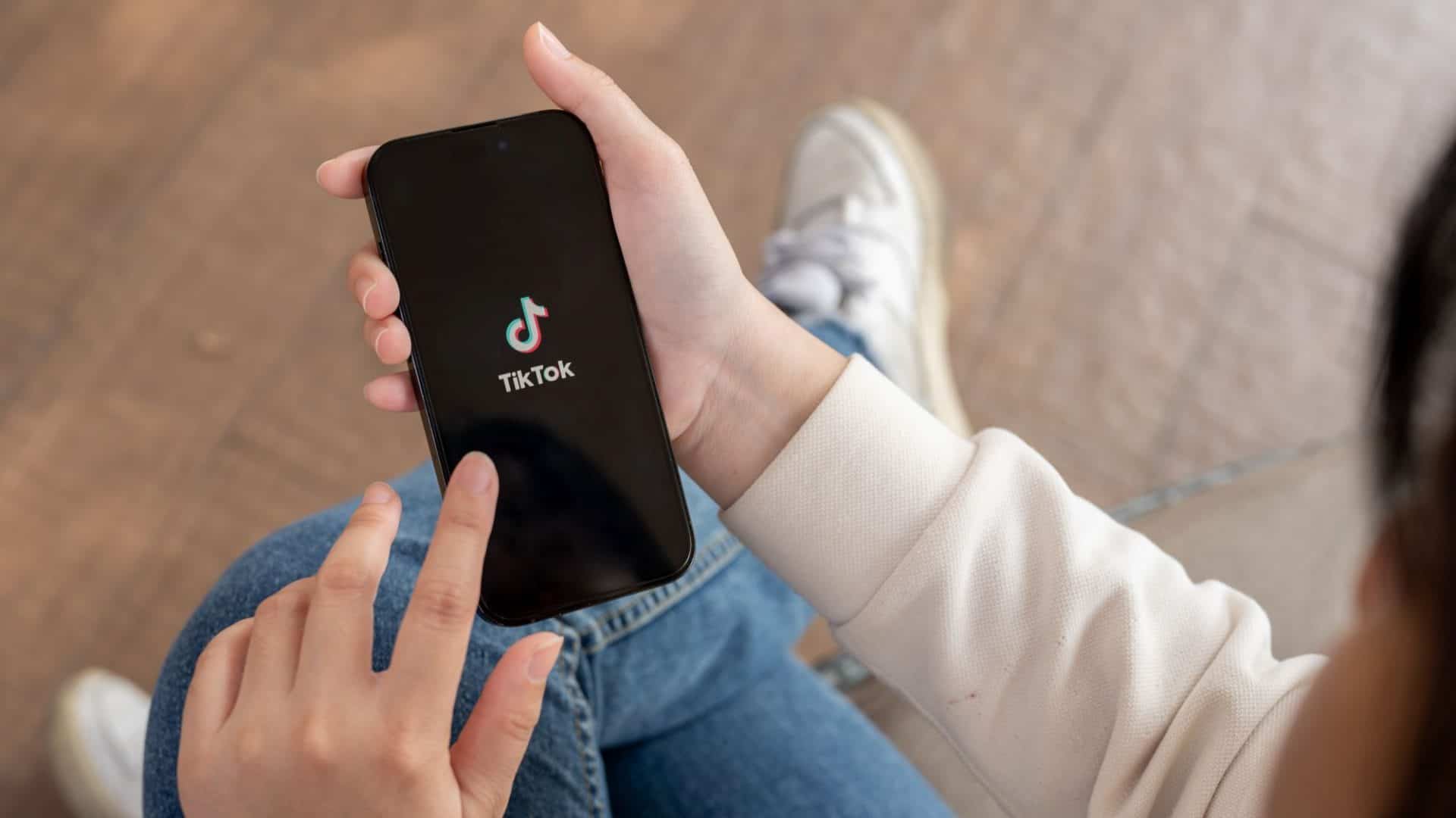 Pessoa segurando celular com logomarca do TikTok na tela – aquela que aparece ao abrir o aplicativo