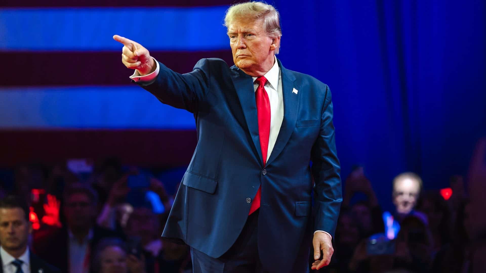 Donald Trump olhando e apontando para o lado esquerdo