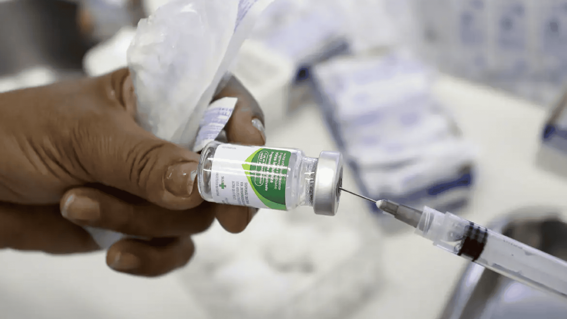Imagem mostra uma mão segurando uma vacina da gripe
