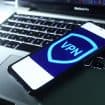 Imagem de um logo de VPN em um smartphone, que está em cima de um notebook