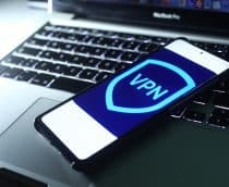 Imagem de um logo de VPN em um smartphone, que está em cima de um notebook