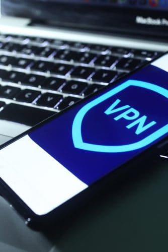 Imagem de um logo de VPN em um smartphone, que está em cima de um notebook