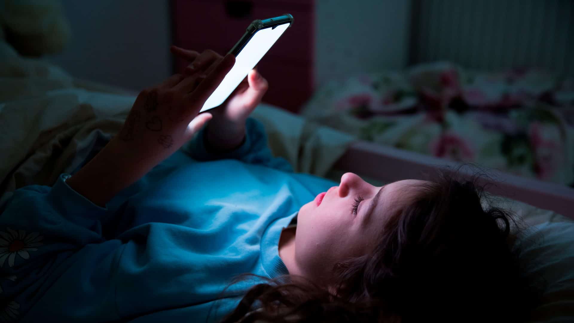 Garota usando celular na cama