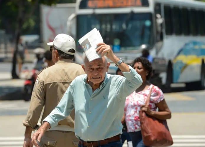 Idoso protegendo cabeça contra o sol usando jornal dobrado em dia quente