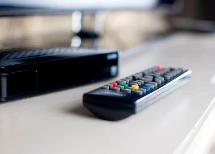 Controle na frente de aparelho de TV Box em móvel numa sala