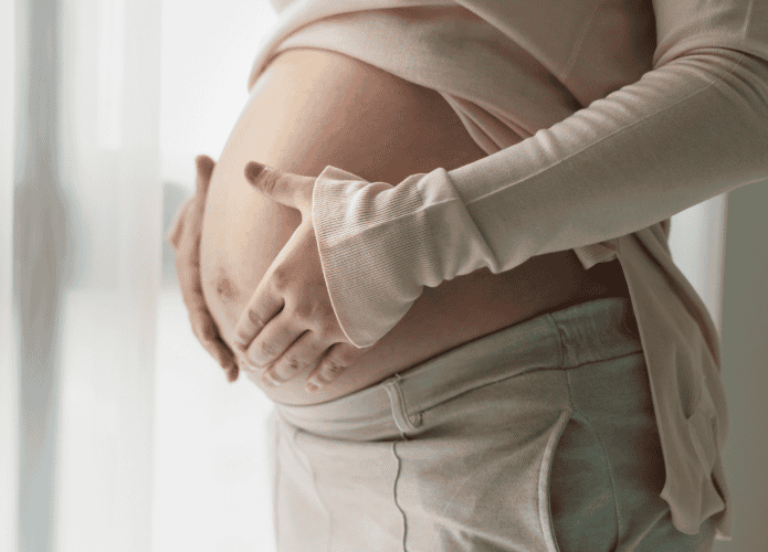 Mulher grávida com as mãos em sua barriga