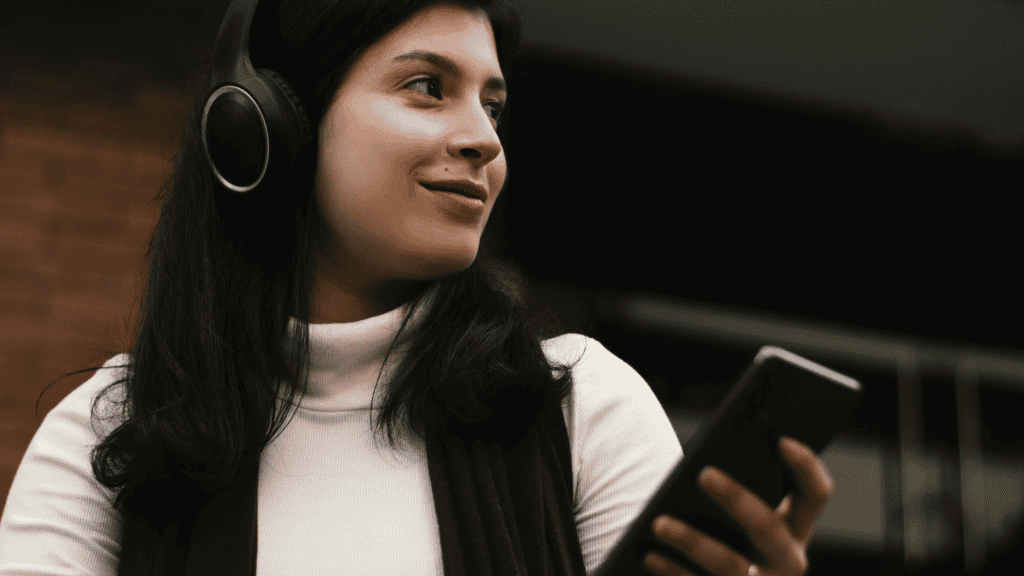 imagem mostra mulher ouvindo música pelo celular com fones de ouvido bluetooth