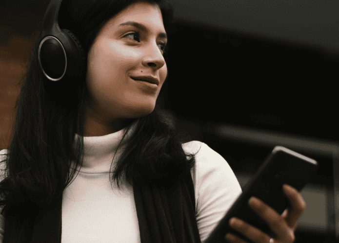 imagem mostra mulher ouvindo música pelo celular com fones de ouvido bluetooth