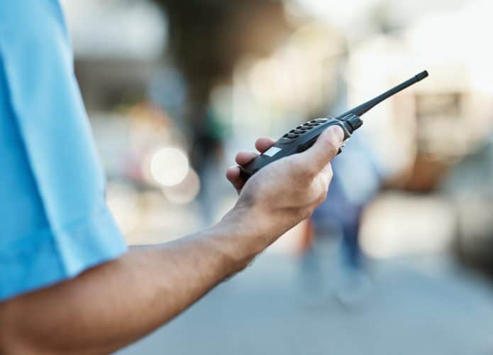 Close de uma pessoa com um walkie talkie em uma rua urbana