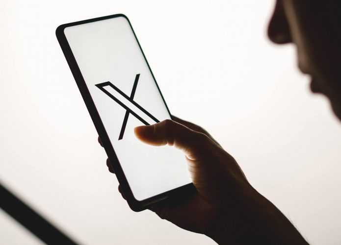 Pessoa vendo um celular com o logo do X