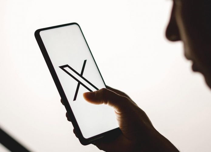Pessoa vendo um celular com o logo do X