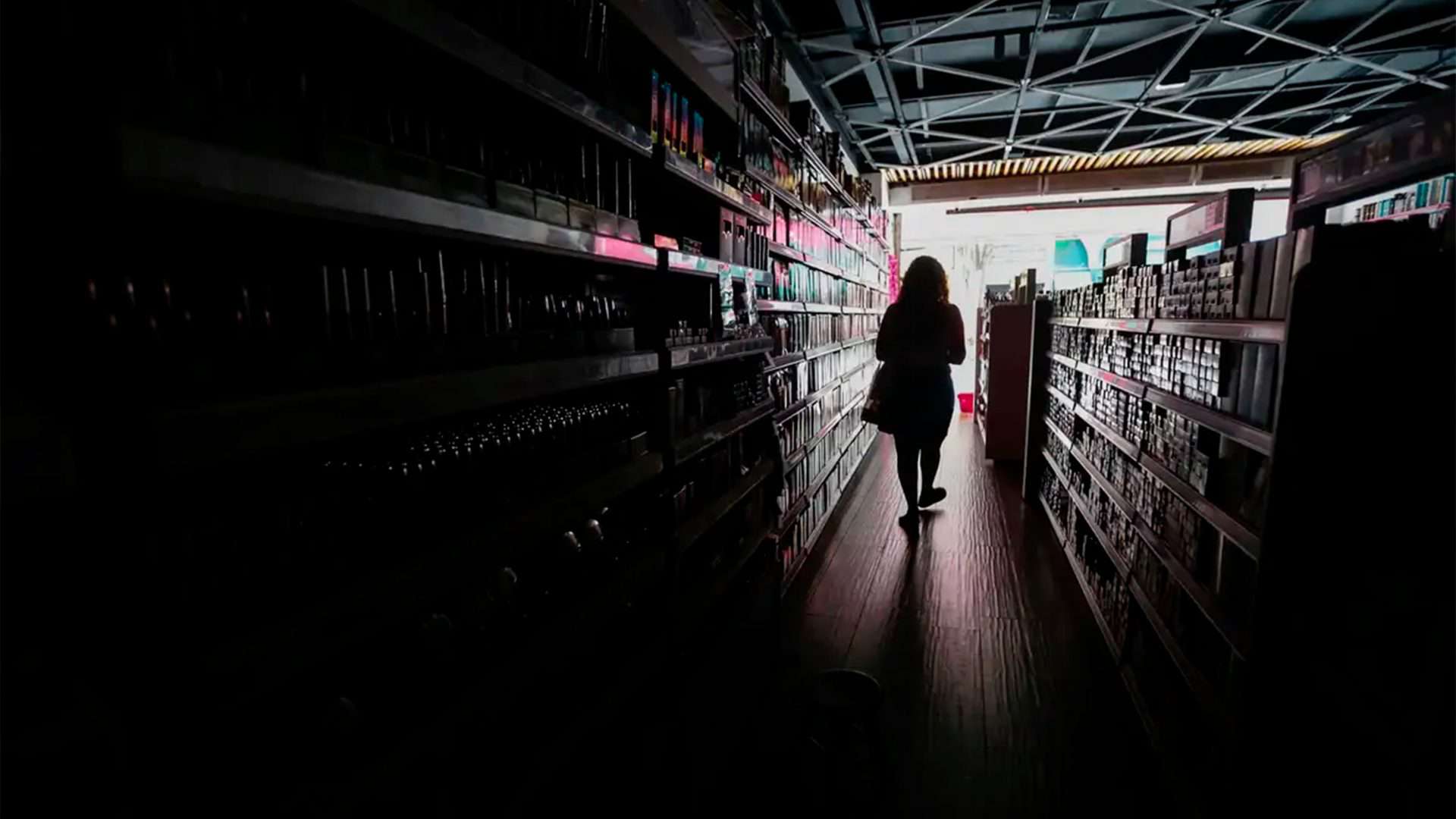 Pessoa andando em loja escura rumo à exterior iluminado durante apagão em São Paulo