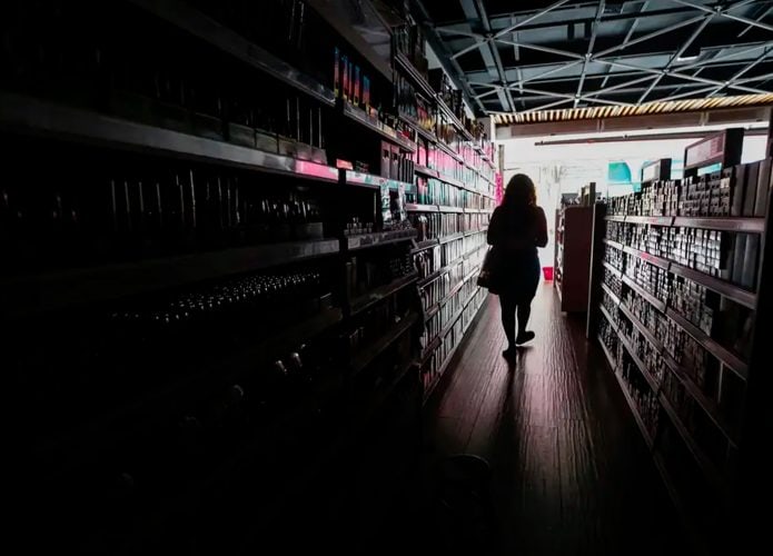 Pessoa andando em loja escura rumo à exterior iluminado durante apagão em São Paulo