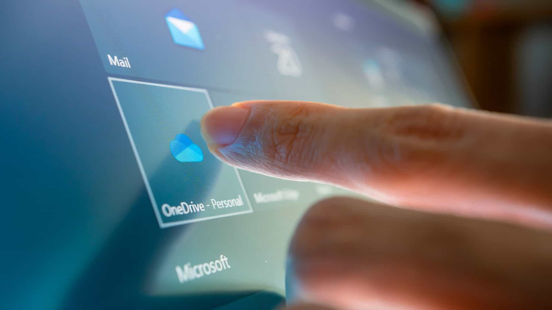 Pessoa tocando em ícone do OneDrive em tela de computador com Windows