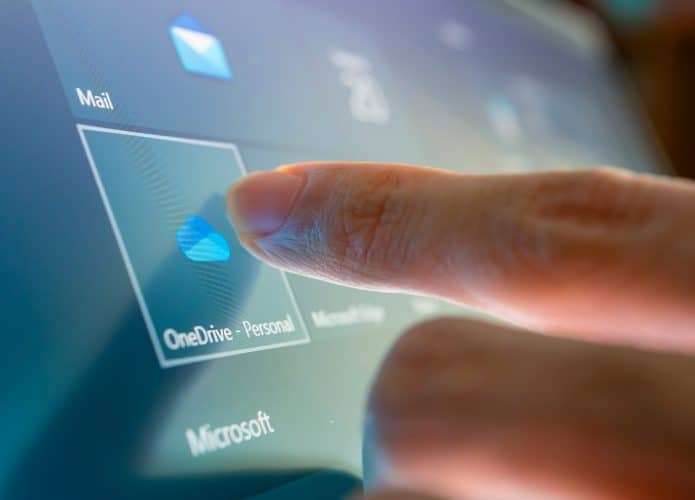 Pessoa tocando em ícone do OneDrive em tela de computador com Windows