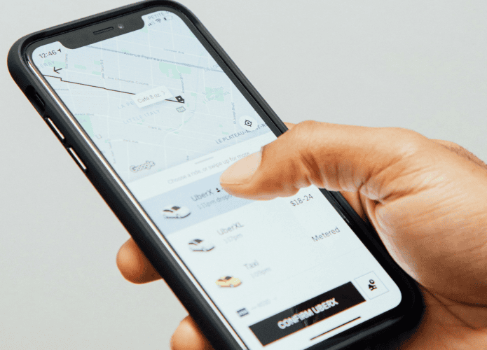 imagem mostra uma pessoa usando o aplicativo de celular Uber para chamar um carro