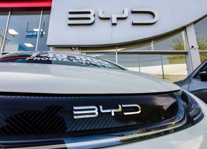 Logo da BYD na fachada de uma loja e na grade de um carro