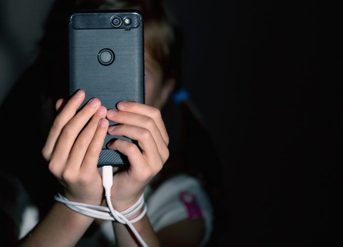 Criança usando celular e amarrada a um fone de ouvido