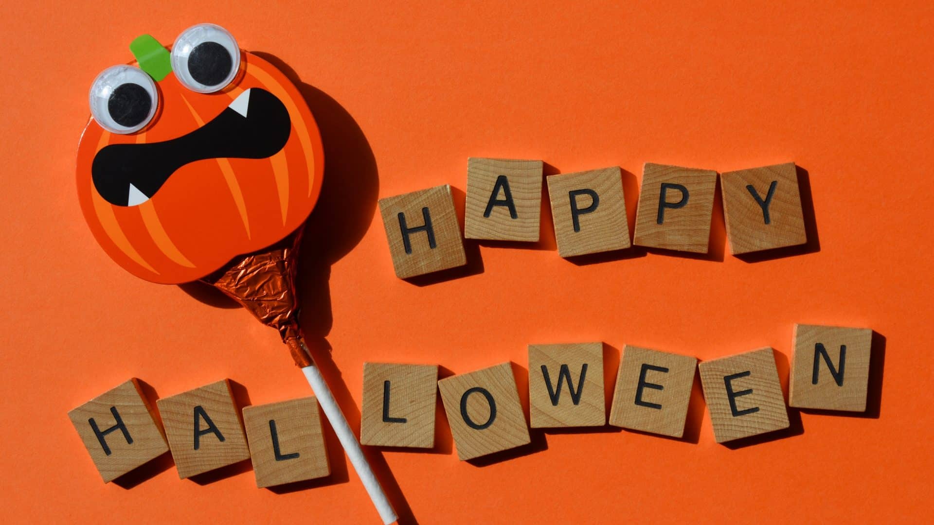 Pirulito com face de uma abóbora de Halloween ao lado dos dizeres 