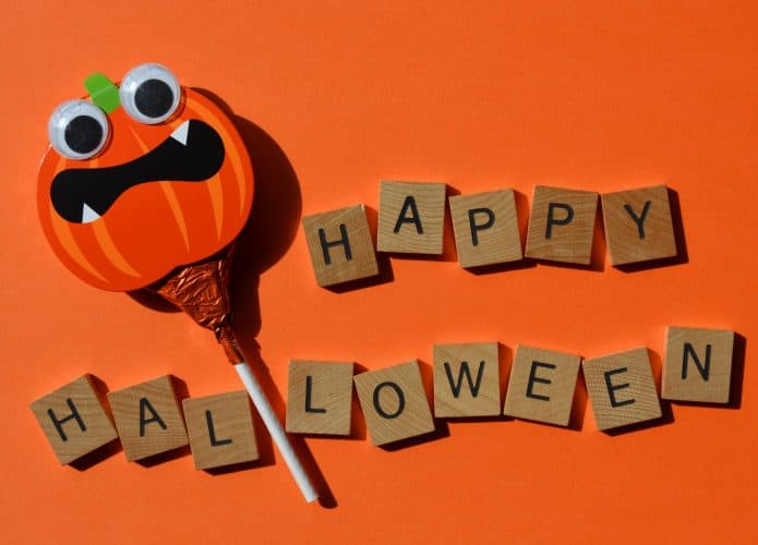 Pirulito com face de uma abóbora de Halloween ao lado dos dizeres