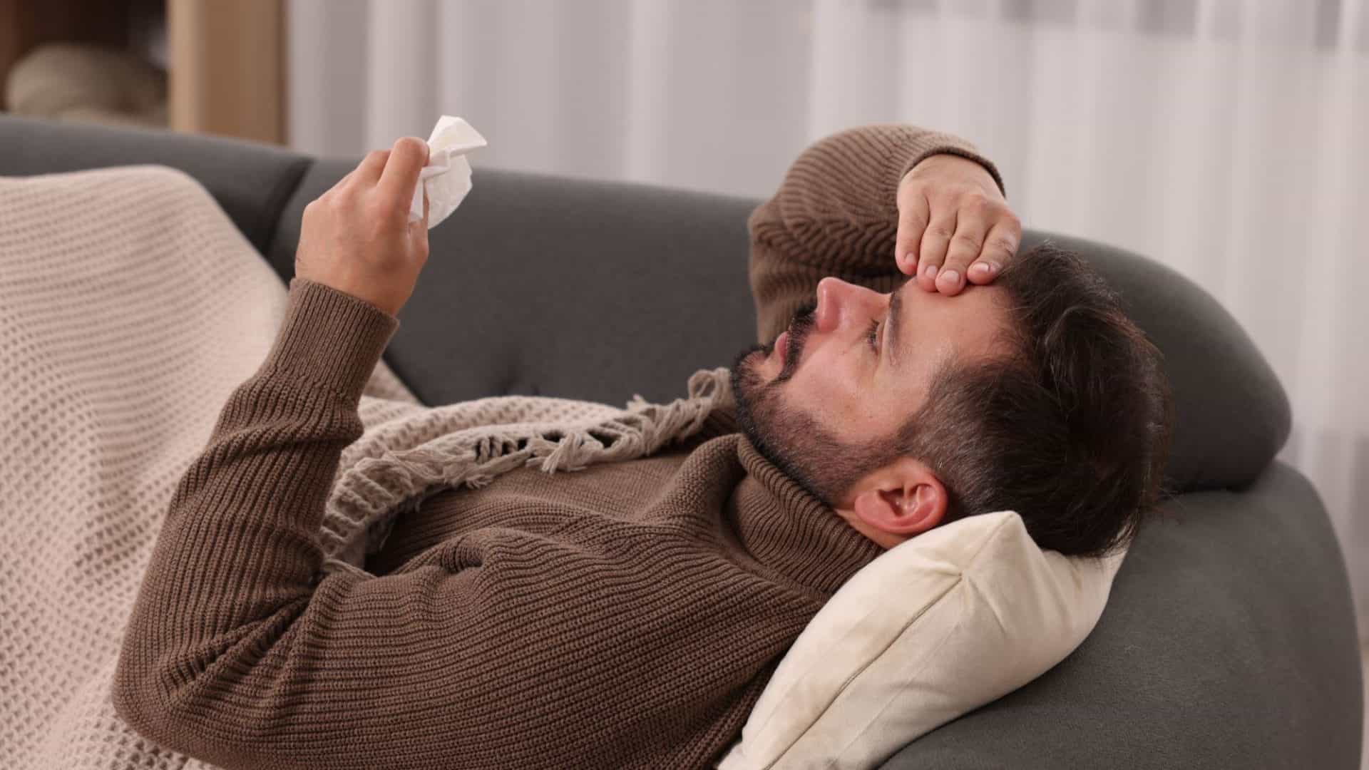 homem deitado no sofá com sintomas de gripe