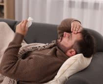 homem deitado no sofá com sintomas de gripe