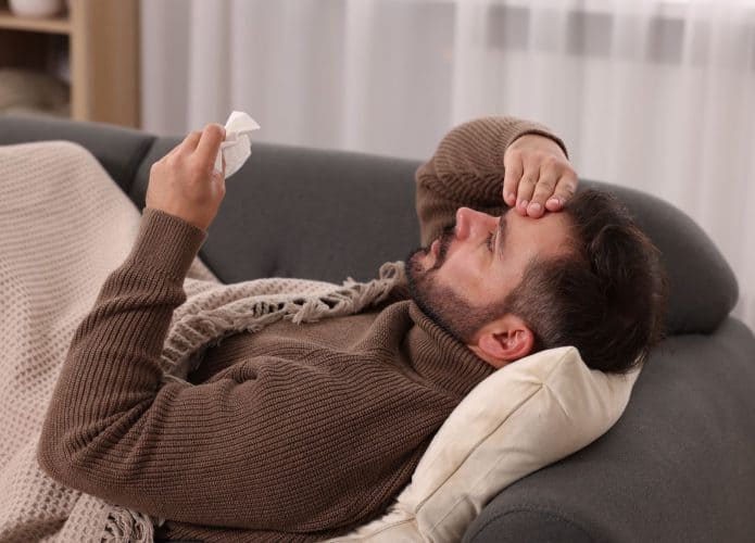 homem deitado no sofá com sintomas de gripe