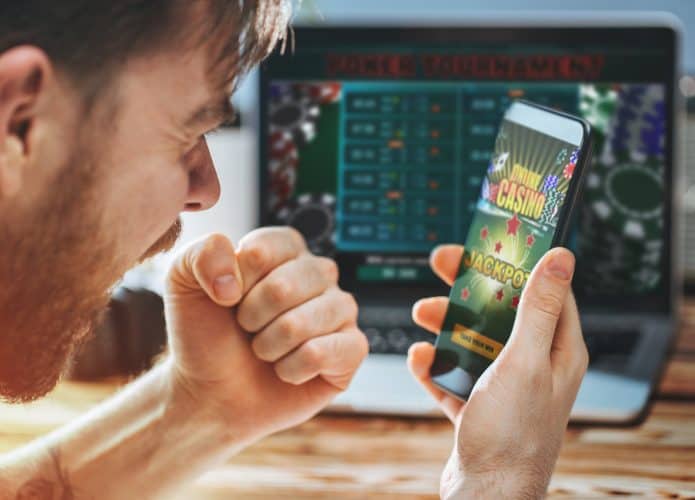 Homem olhando o smartphone e celebrando a conquista de uma aposta