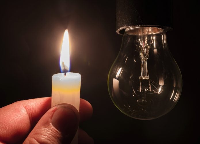 lâmpada apagada e uma vela acesa