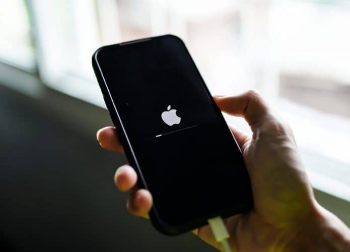 Tela inicial do iPhone após ser ligado; aparelho está na mão de uma pessoa