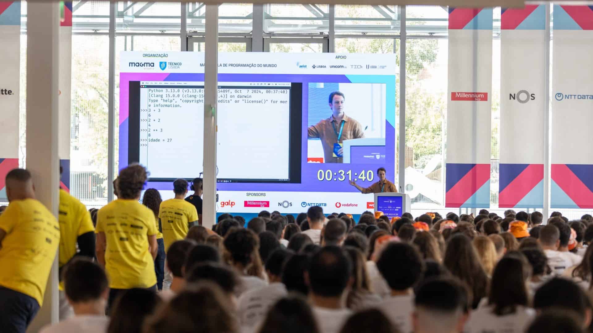 Professor, ao fundo, explicando a matéria; em primeiro plano e desfocado, vários alunos