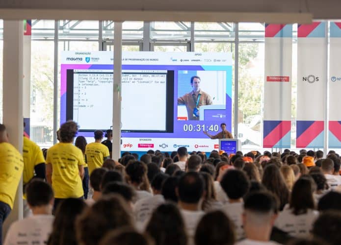 Professor, ao fundo, explicando a matéria; em primeiro plano e desfocado, vários alunos