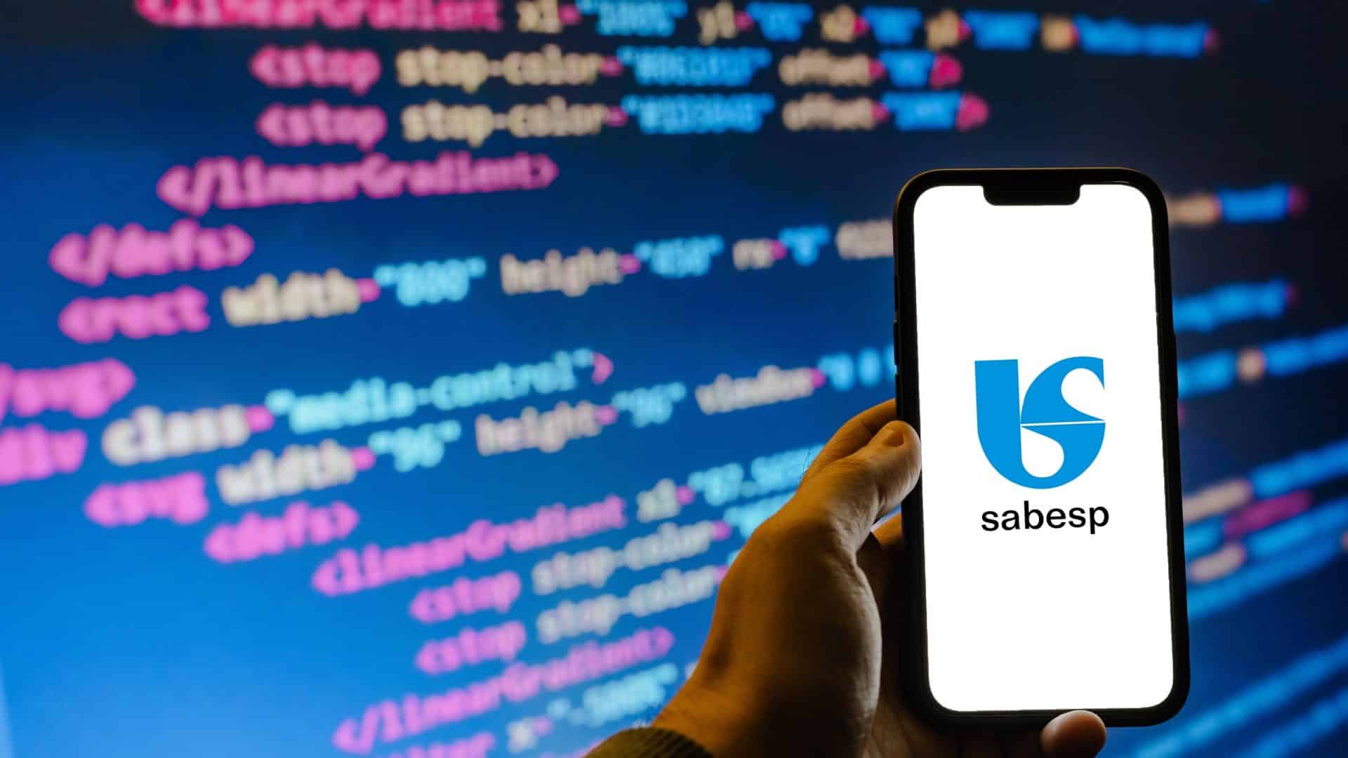 Logo da Sabesp em um smartphone; no fundo códigos de computador