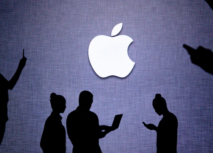 Silhueta de pessoas usando notebooks e celulares embaixo de logotipo da Apple