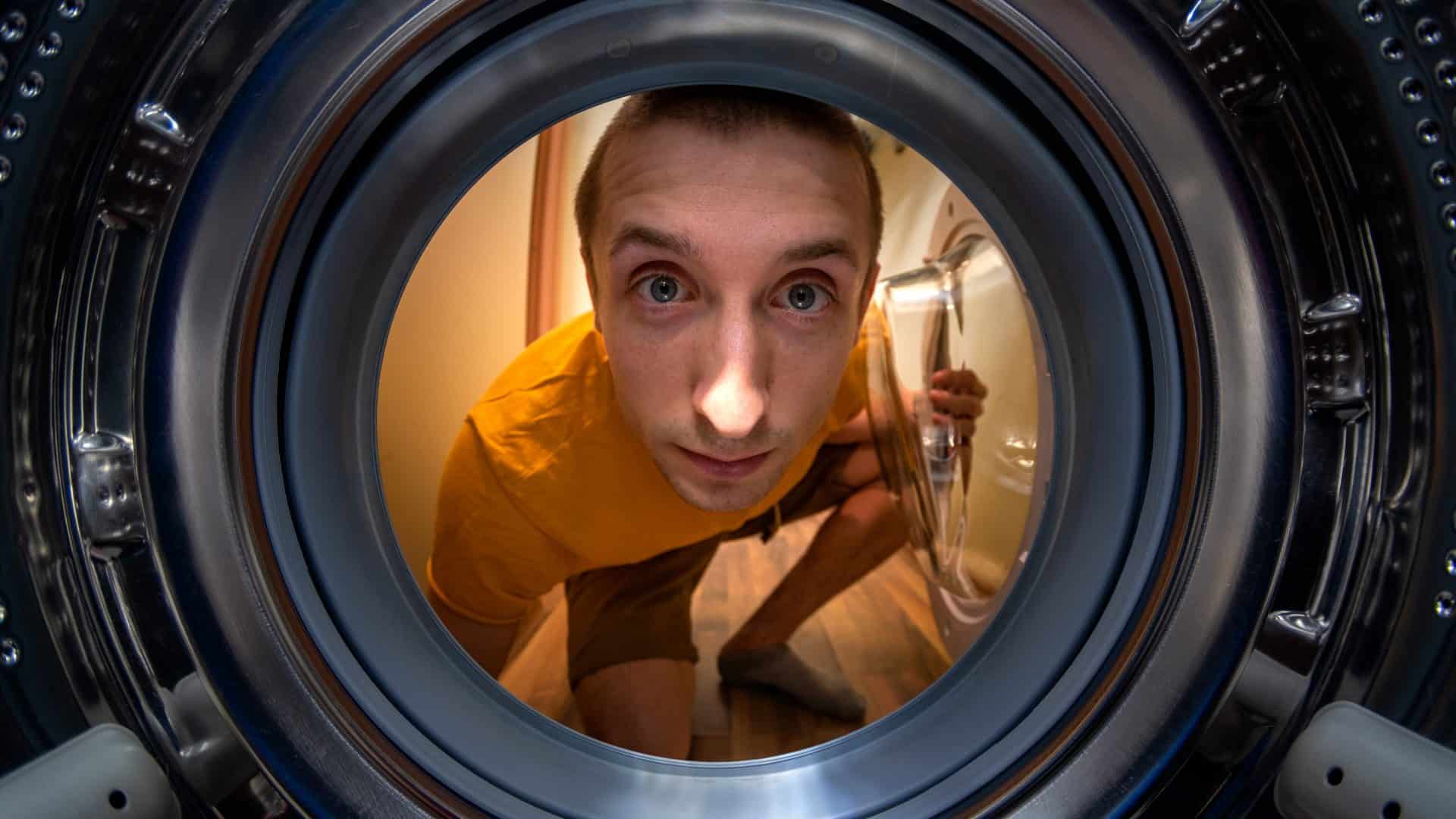 Pessoa olhando para dentro de uma máquina de lavar em foto estilo ponto de vista de dentro da máquina