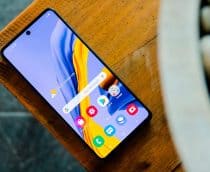 Celular Samsung Galaxy M51 em cima de mesa de madeira com tela acesa na tela inicial