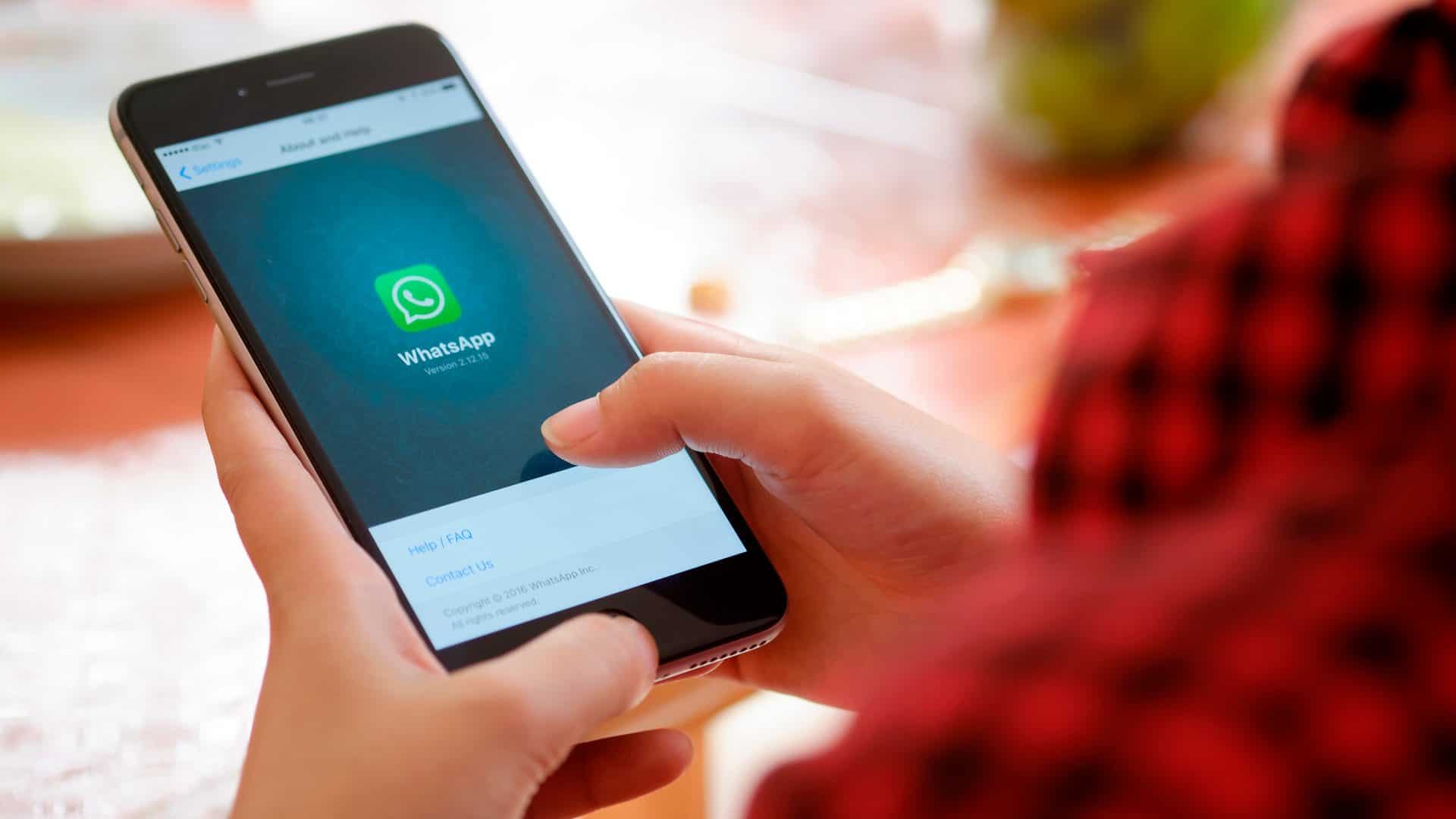 Pessoa acessando página sobre Whatsapp em modelo antigo de iPhone