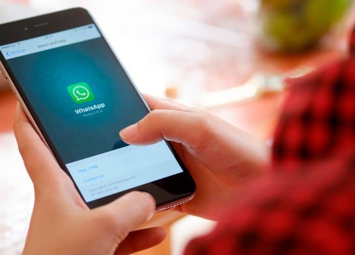 Pessoa acessando página sobre Whatsapp em modelo antigo de iPhone