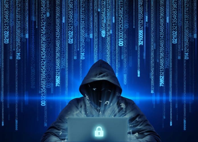 Pessoa com capuz atrás de um notebook