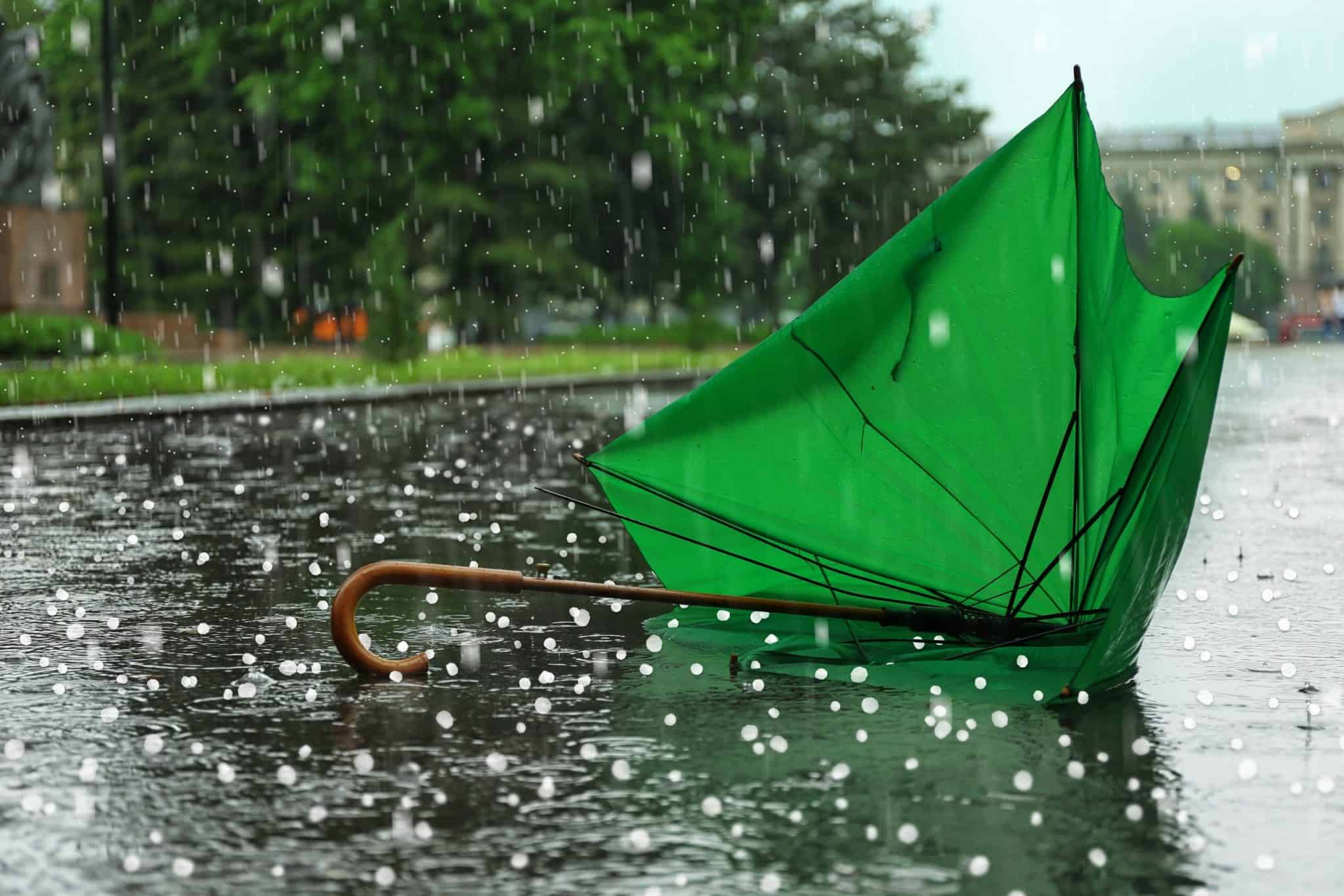 Granizo e um guarda-chuva verde quebrado no chão