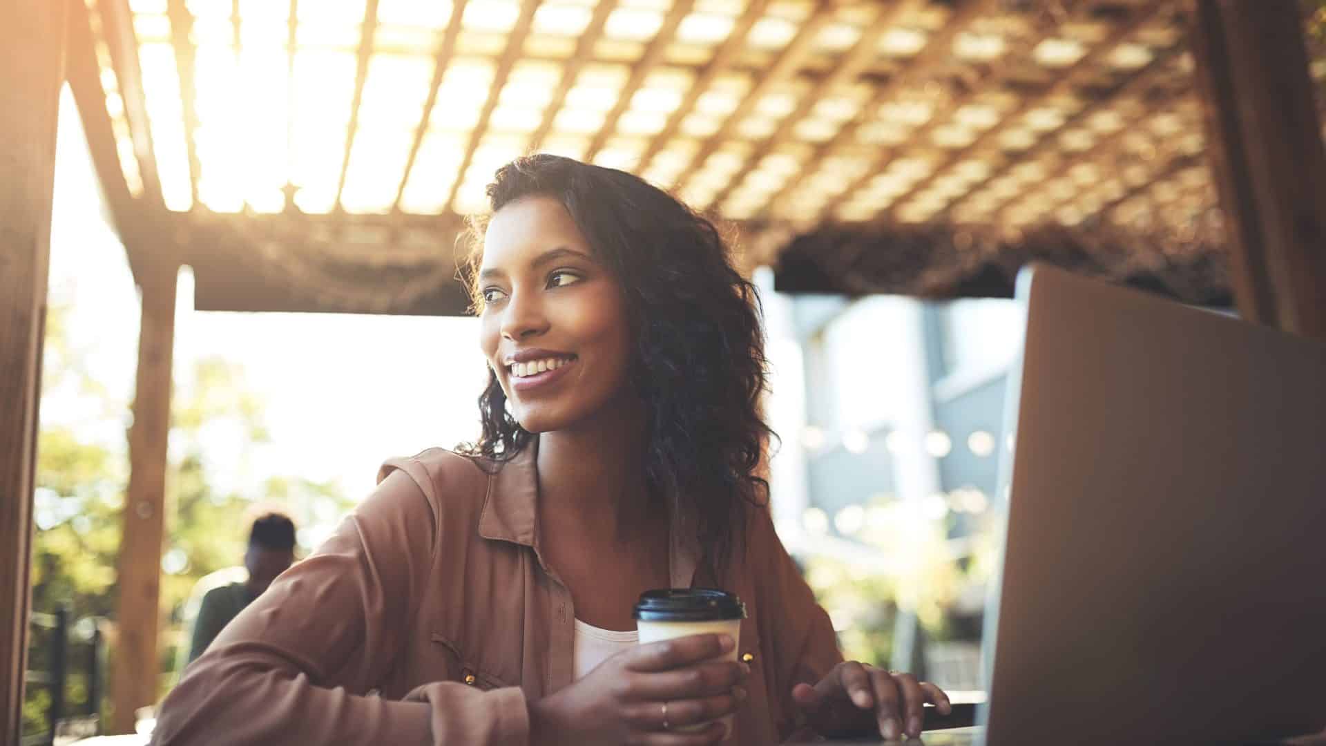 Mulher trabalha remotamente em café (vaga remota)