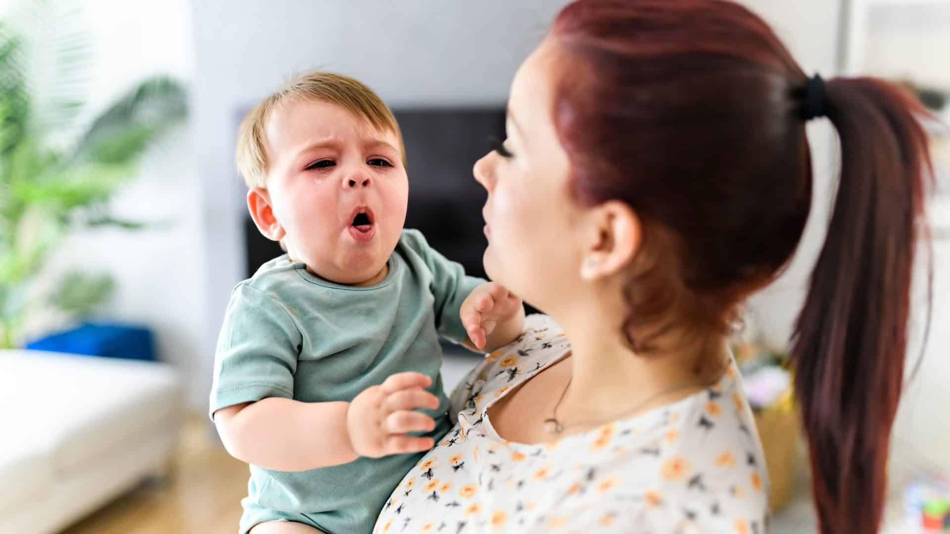 Mãe segura bebê que está tossindo, os casos de coqueluche têm aumentado