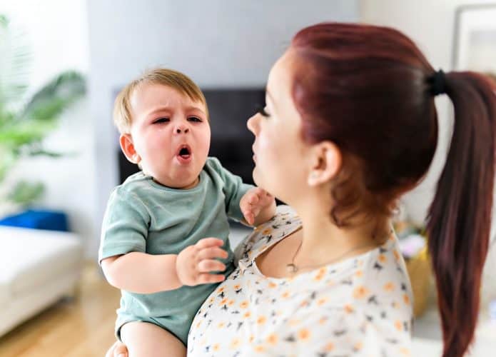 Mãe segura bebê que está tossindo, os casos de coqueluche têm aumentado