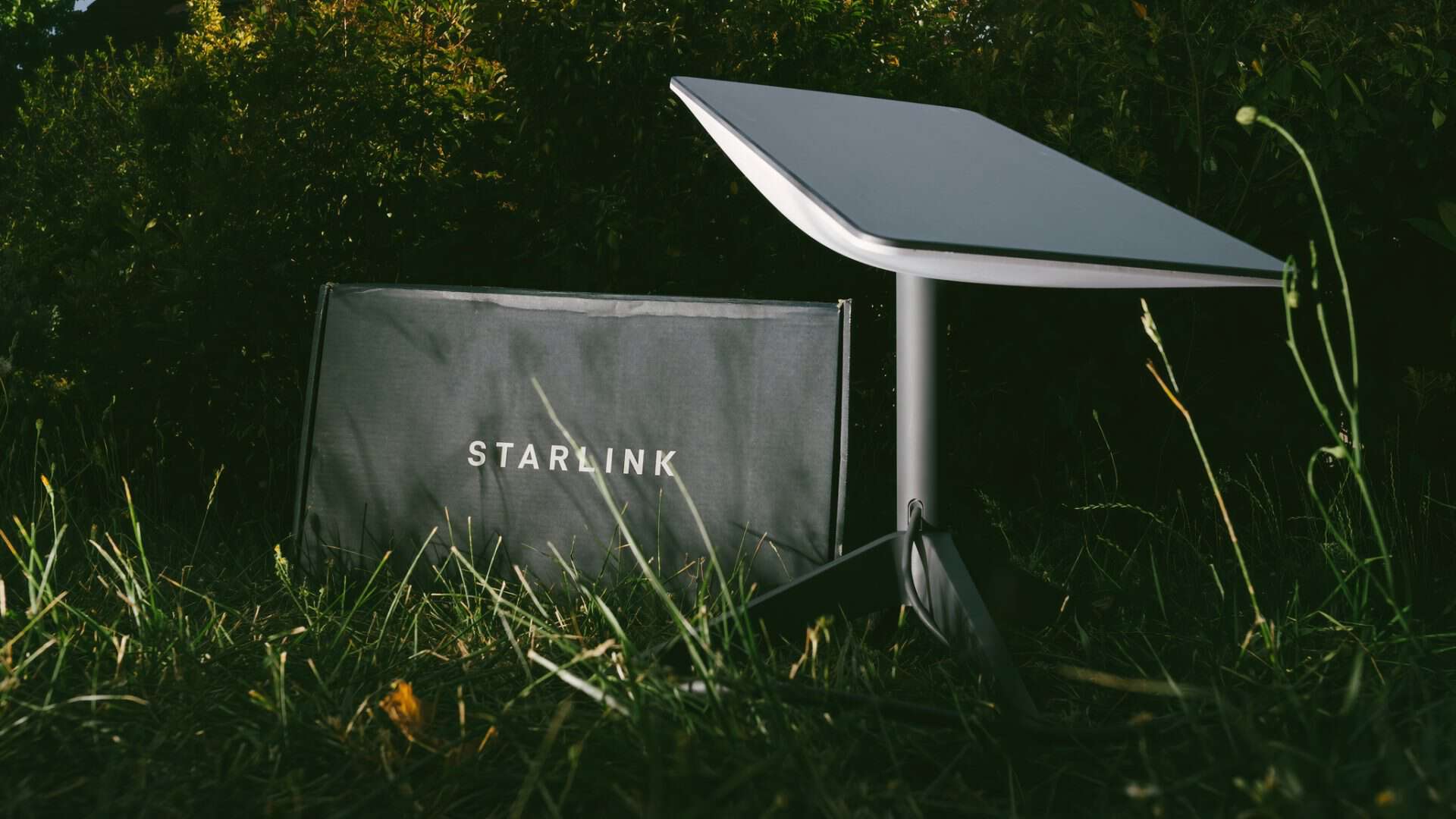 Antena e modem Starlink instalados em um gramado à noite
