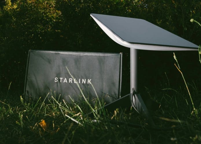 Antena e modem Starlink instalados em um gramado à noite
